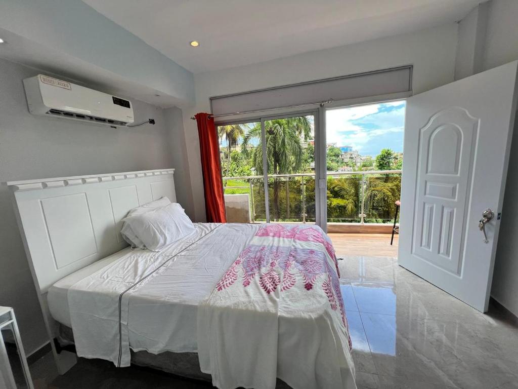 サンタ・バーバラ・デ・サマナにあるHABITACIONES CON VISTA a LA BAHIA LA FAMILIAの白いベッドと大きな窓のある寝室