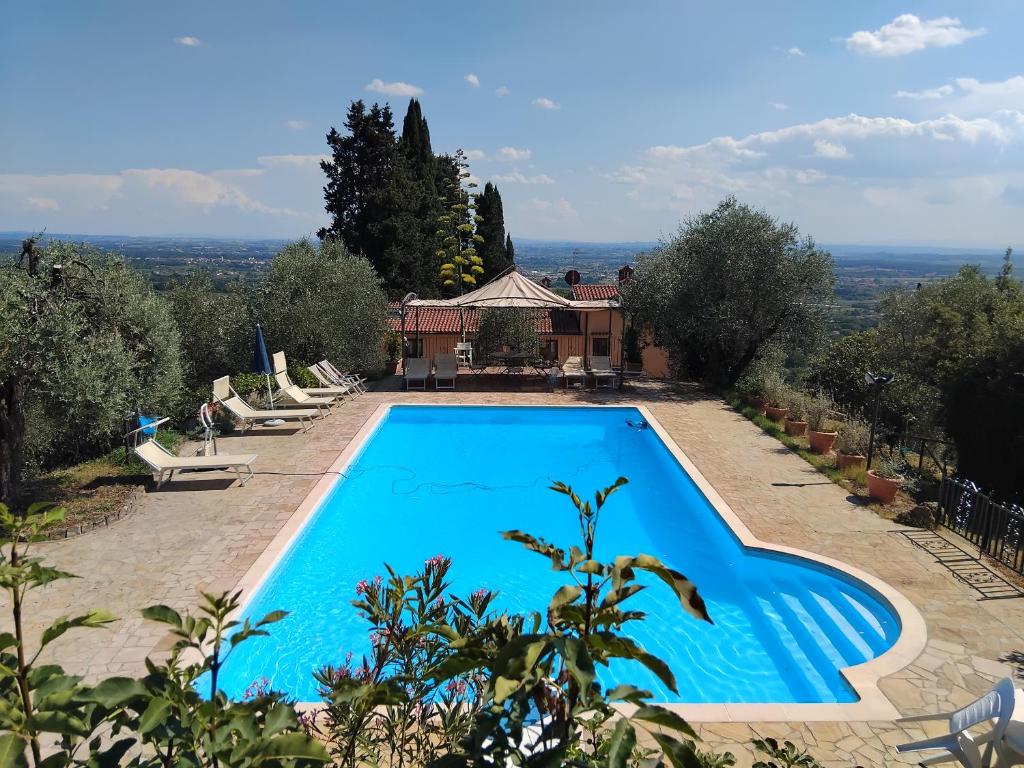 une grande piscine bleue devant une maison dans l'établissement Villa Pilar in Toscana con piscina ultrapanoramica, à Montevettolini