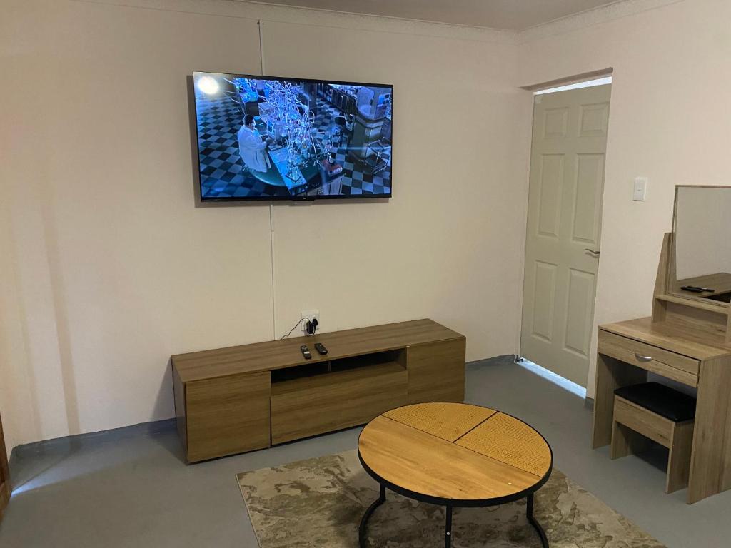 a living room with a table and a tv on the wall at Zalu Lodge in Lusikisiki