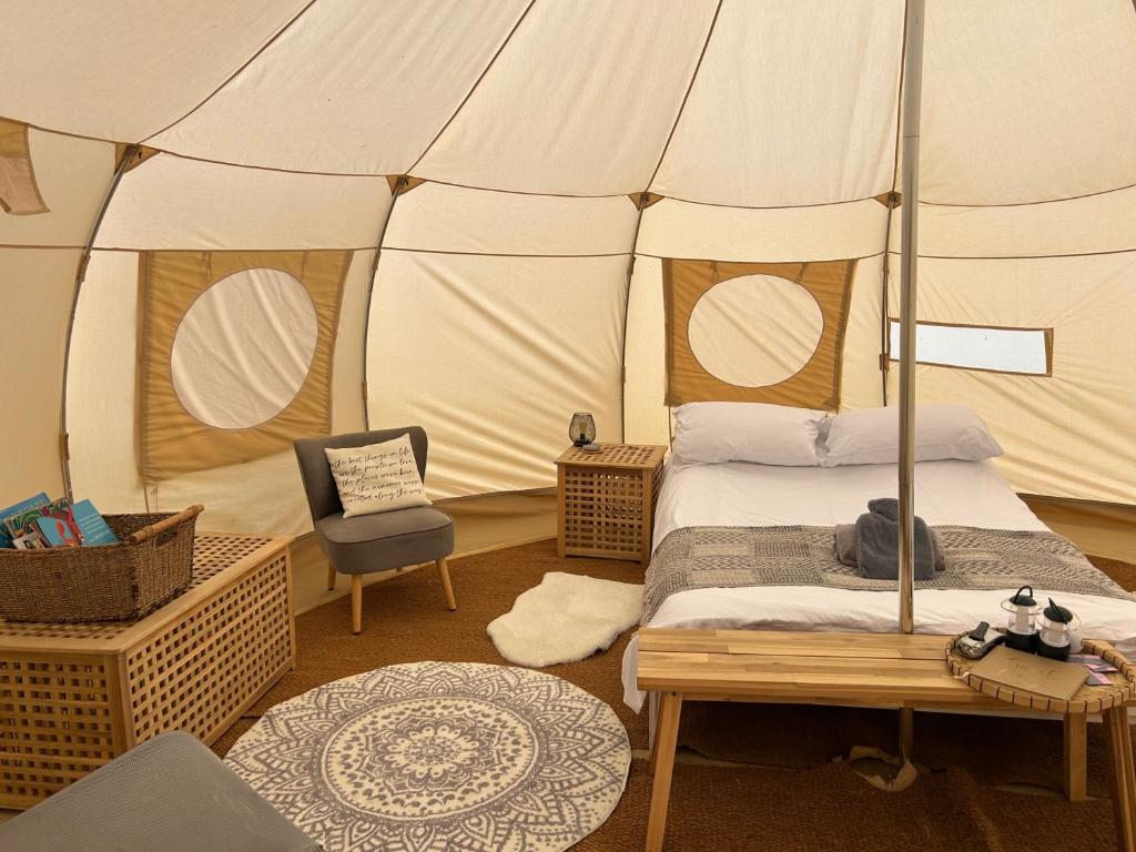 a bedroom with a bed and a chair in a tent at Beautiful Bell Tent Stay in Cowbridge