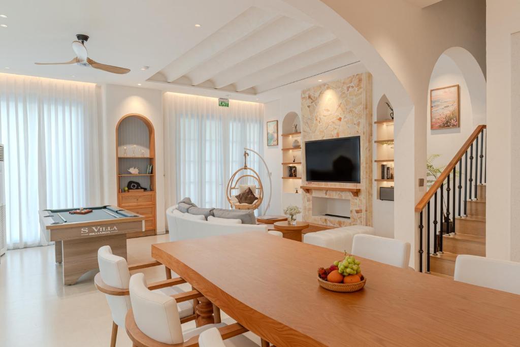 un salon avec une table en bois et des chaises blanches dans l'établissement Ha Long 6BRS Beach Villa With Pool, Jacuzzi and Sauna, à Hạ Long