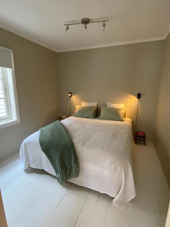 a bedroom with a bed with white sheets and green pillows at A cosy flat in the heart of Stavanger in Stavanger