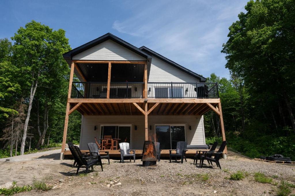 una casa con terraza y sillas delante en Spa and Lakefront - Oasis des chutes, en Lac-Saint-Paul