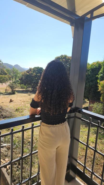 a woman standing on a balcony with curly hair at Loft Santorini no centro com Café da manhã in Alto Paraíso de Goiás