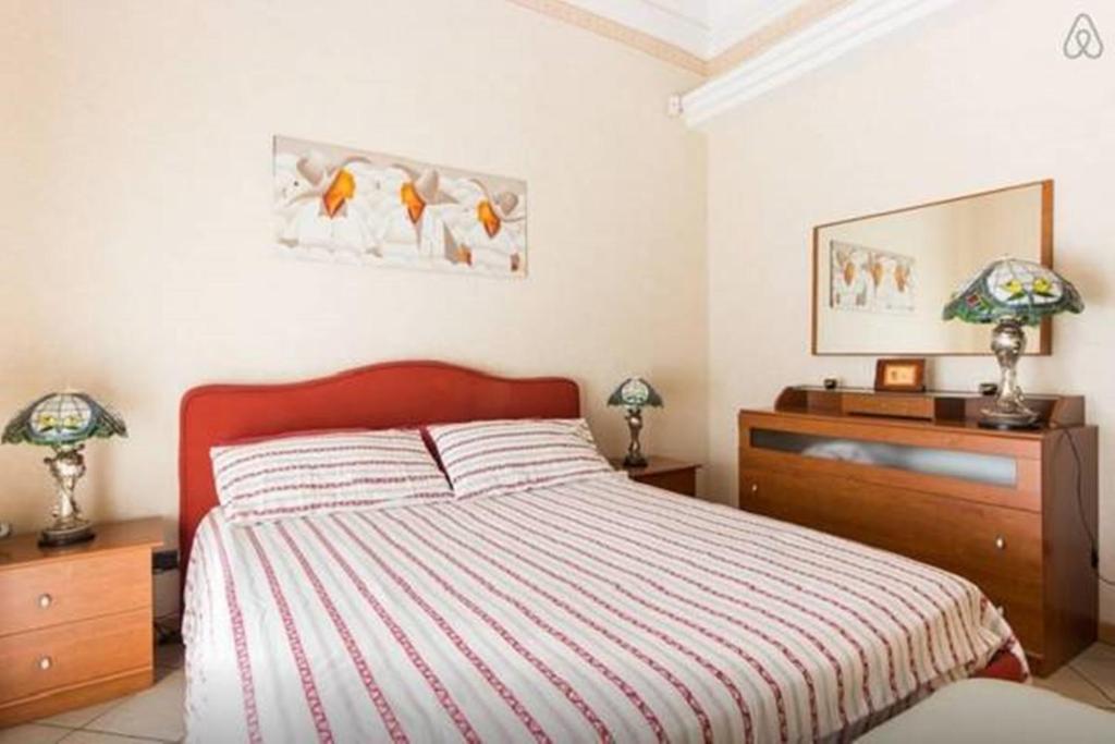 カターニアにあるApartment Gemmellaroのベッドルーム1室(ベッド1台、ドレッサー、ランプ2つ付)