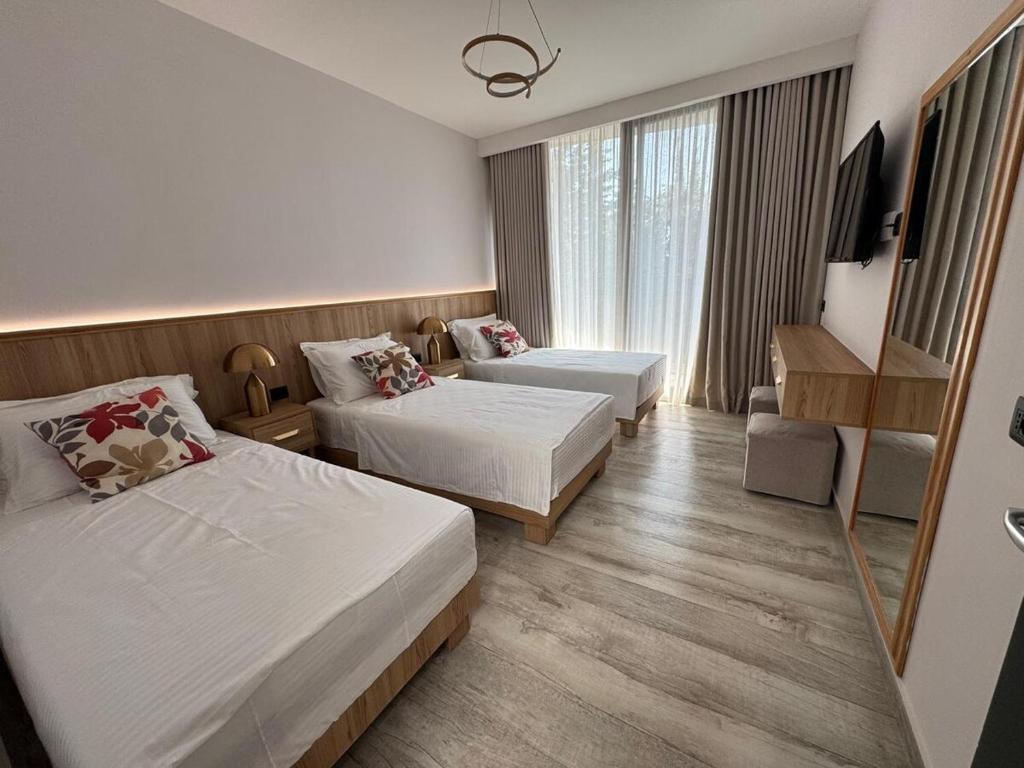 a hotel room with two beds and a television at Escape by Form Villa Olea 3 with pool in Dhërmi