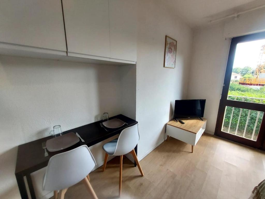 a room with a desk and two chairs and a television at Studio Brasilia in Mont-de-Marsan