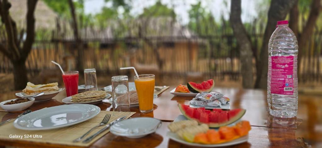 蒂瑟默哈拉默Thumbaya Resort Yala的一张木桌，上面摆放着食物和一瓶水