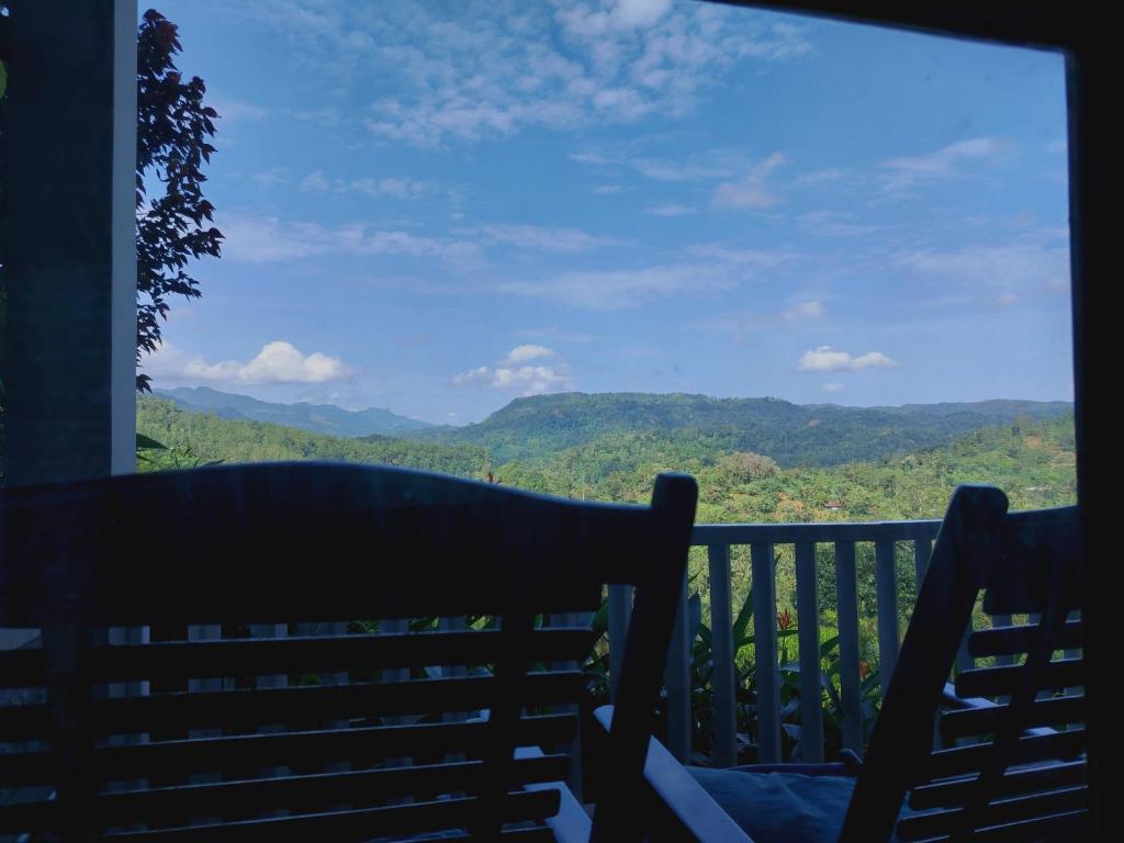 a bench on a balcony with a view of mountains at Rainforest Nature House in Deniyaya