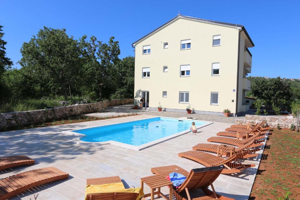 a villa with a swimming pool in front of a building at Apartments Bellator in Šilo