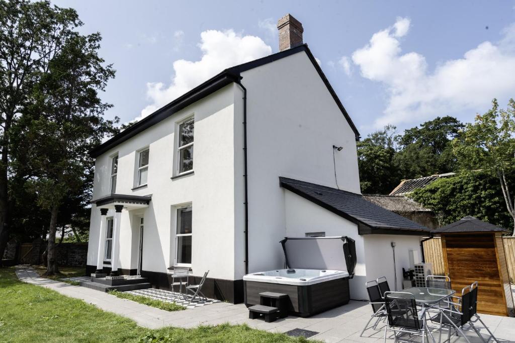a white house with a bath tub on a patio at Devon Hot Tub Retreat in Bideford