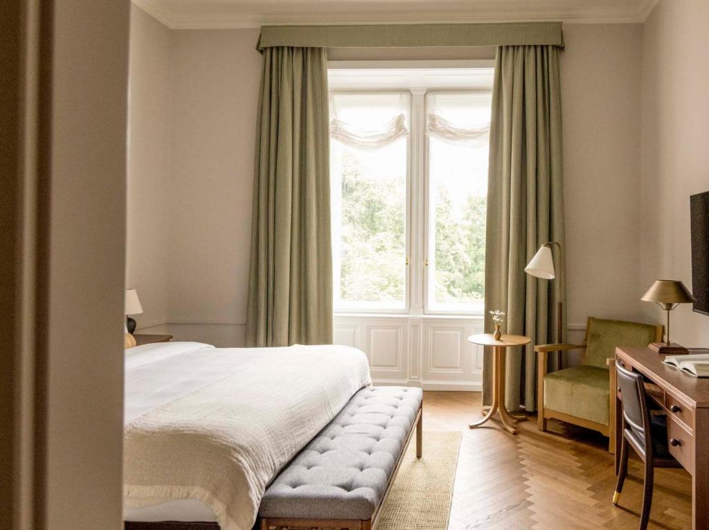 a bedroom with a bed and a window and a chair at Miiro Palais Rudolf NEW OPENING in Vienna
