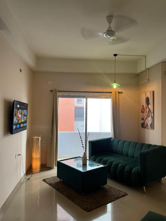 sala de estar con sofá verde y mesa de centro en The Aura 2BHK near Paltan bazar, en Guwahati