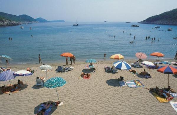 a group of people on a beach with umbrellas at Villa Franka in Lopud