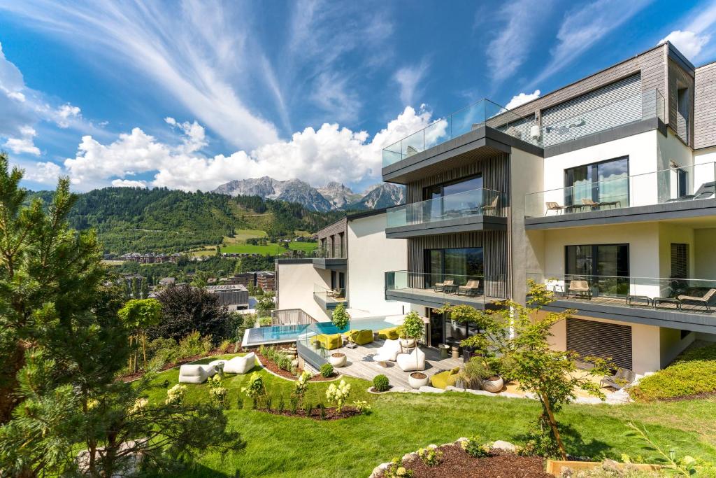 an exterior view of a house with mountains in the background at Boutique Aparthotel Chalets Coburg in Schladming