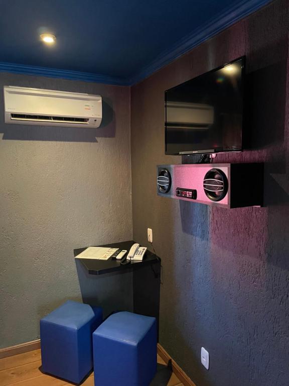 a room with a desk with a air conditioner and blue stools at Agha Motel in Canela