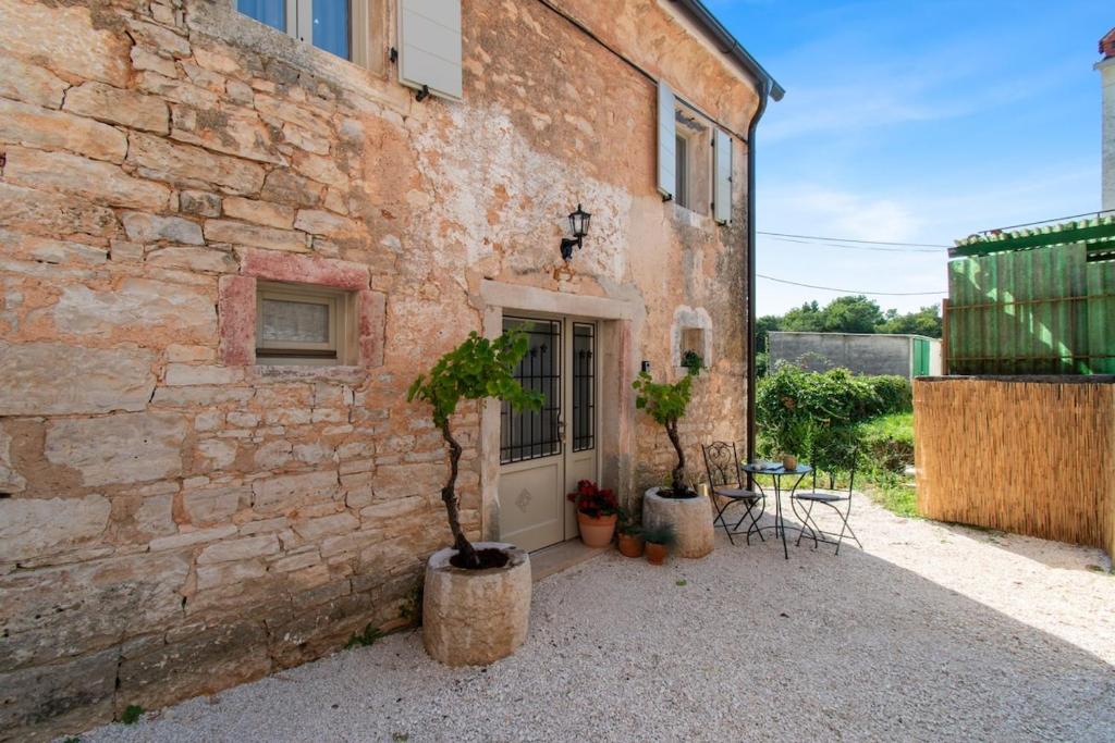 un edificio de ladrillo con dos macetas delante de él en Istrian House Casa Morosina by Istrabook, en Svetvinčenat