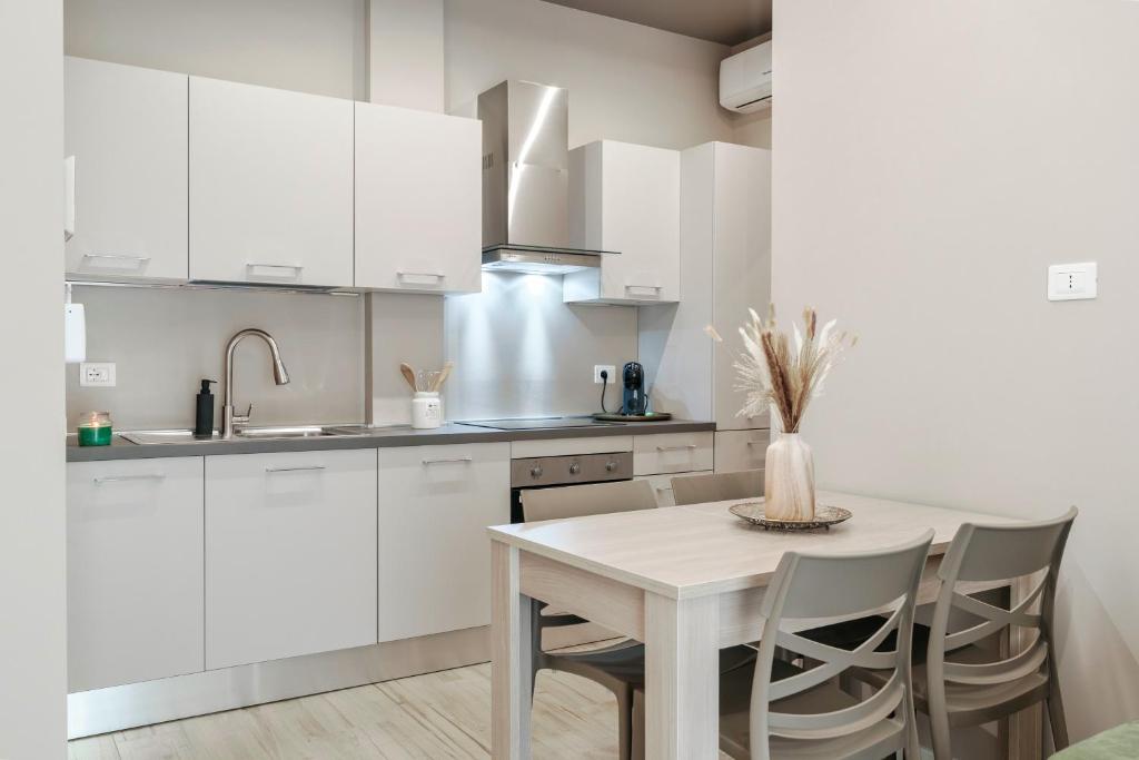 a kitchen with white cabinets and a table and chairs at ESSENZA MODERNA Design & Quiete in Brescia
