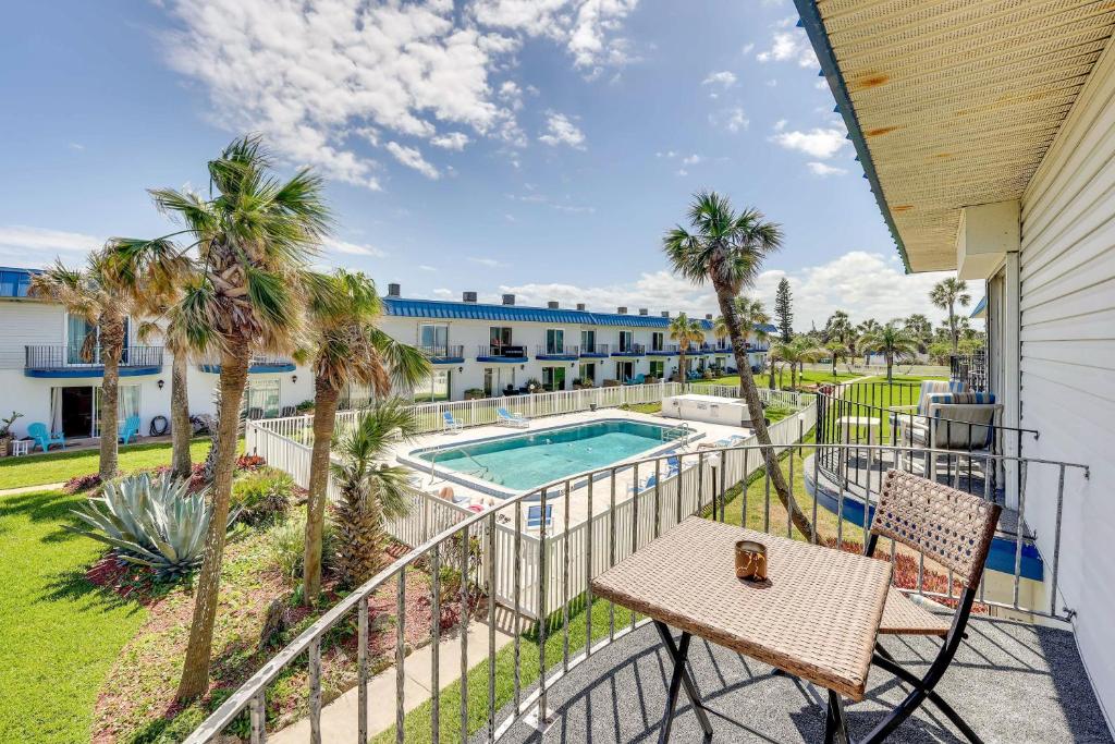オーモンド・ビーチにあるOceanfront Ormond Beach Condo Patio, Pool Access!のバルコニー(テーブル、椅子付)、スイミングプールが備わります。