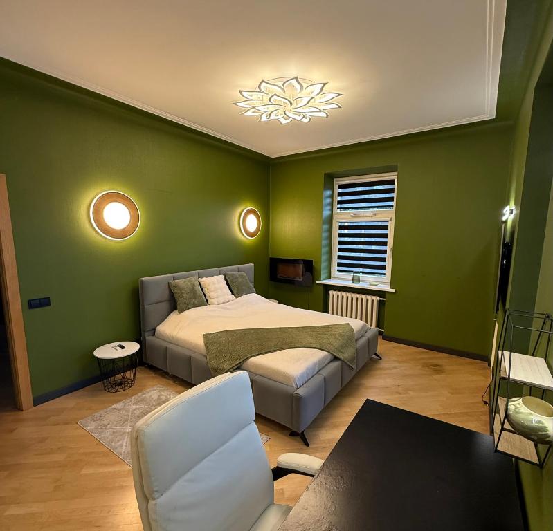 a green bedroom with a bed and a chair at Downtown Kaunas - Maironis 10 in Kaunas