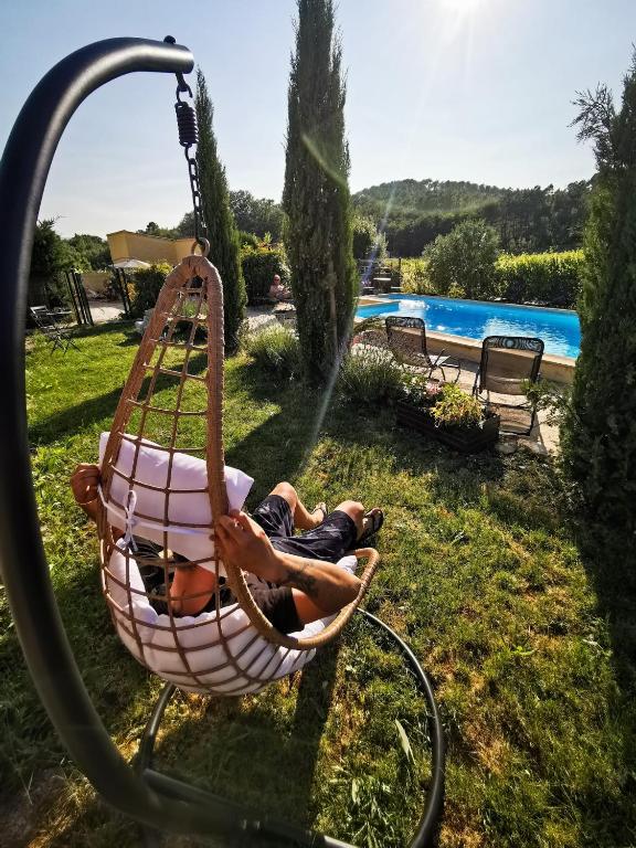 a man laying in a hammock by a pool at appartement avec piscine commune le chêne blc in Gargas