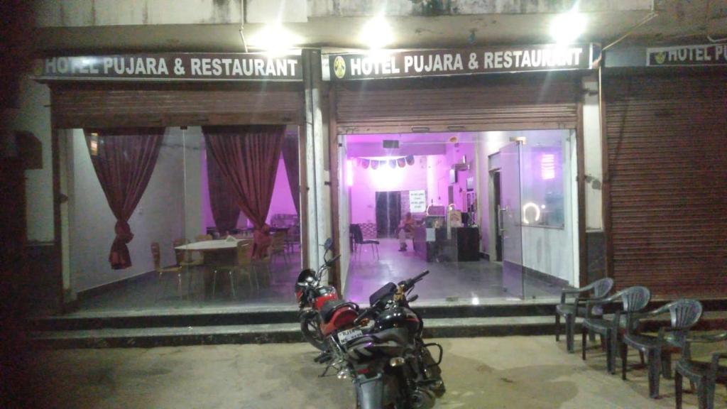 a motorcycle parked in front of a store front at Pujara Hotel in Diggi