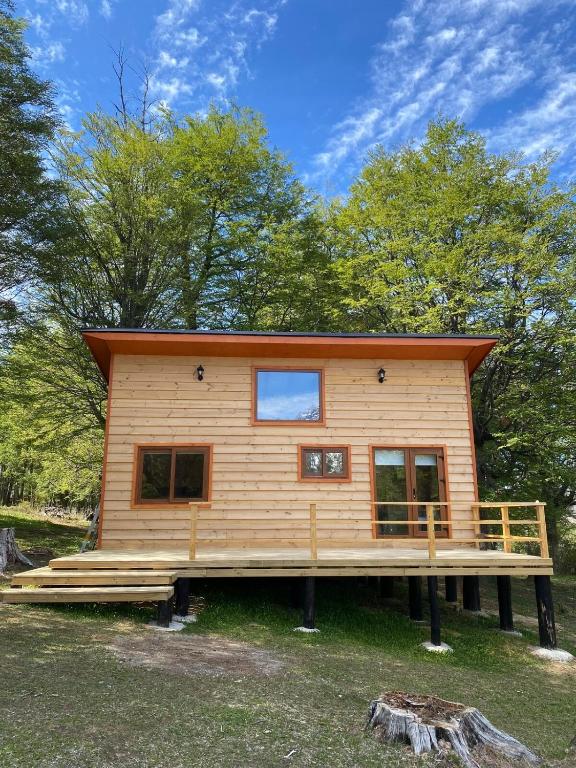 a cabin in the woods with a large deck at Mini Casa a 6 kilómetros de Villa Cerro Castillo Aysen Carretera Austral in Villa Cerro Castillo