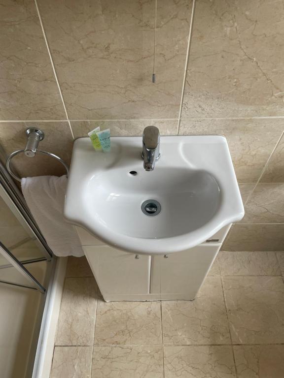 a white sink in a bathroom with tile walls at Crawford House- ScholarLee Living Apartments in Cork