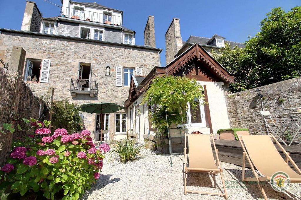 a house with two chairs and flowers in front of it at Chez isabelle in Dinan