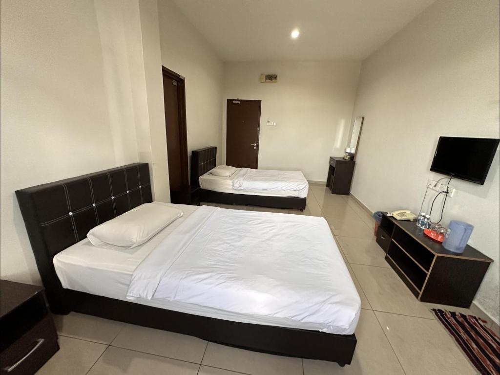 a bedroom with two beds and a flat screen tv at Dancenter Hotel Formosa Bukit Katil in Malacca