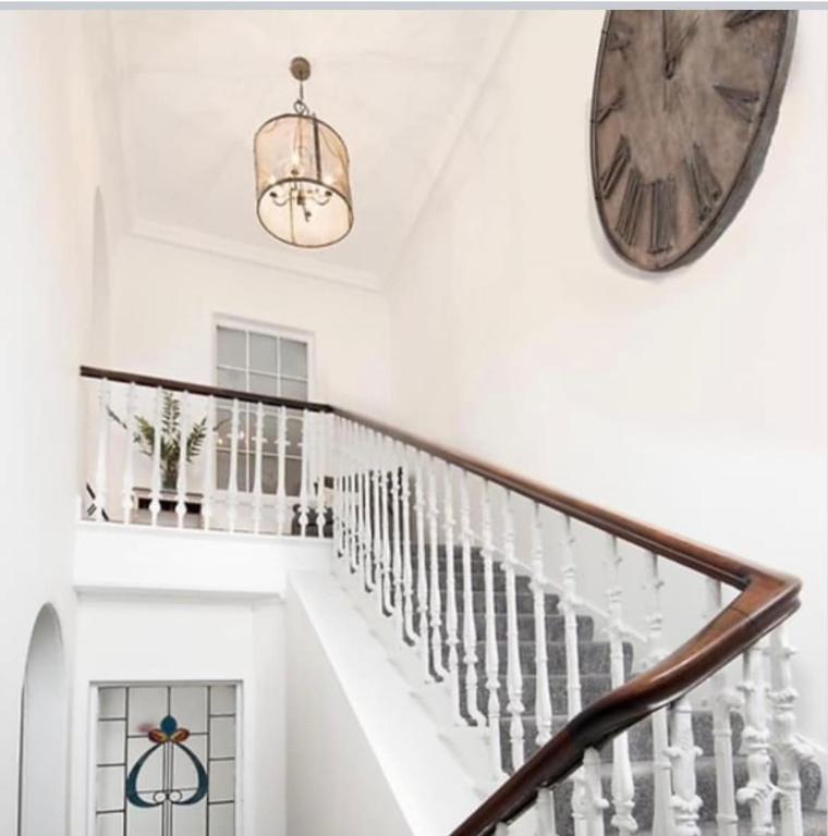 a white staircase with a clock on the wall at Stylish Town Apt in Hawick