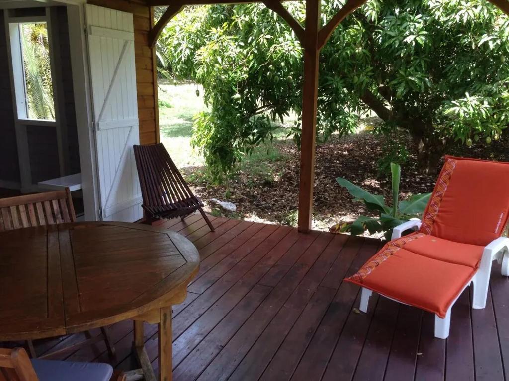 a wooden deck with chairs and a table and chairs at Maison charmante à Sainte-Anne in Sainte-Anne