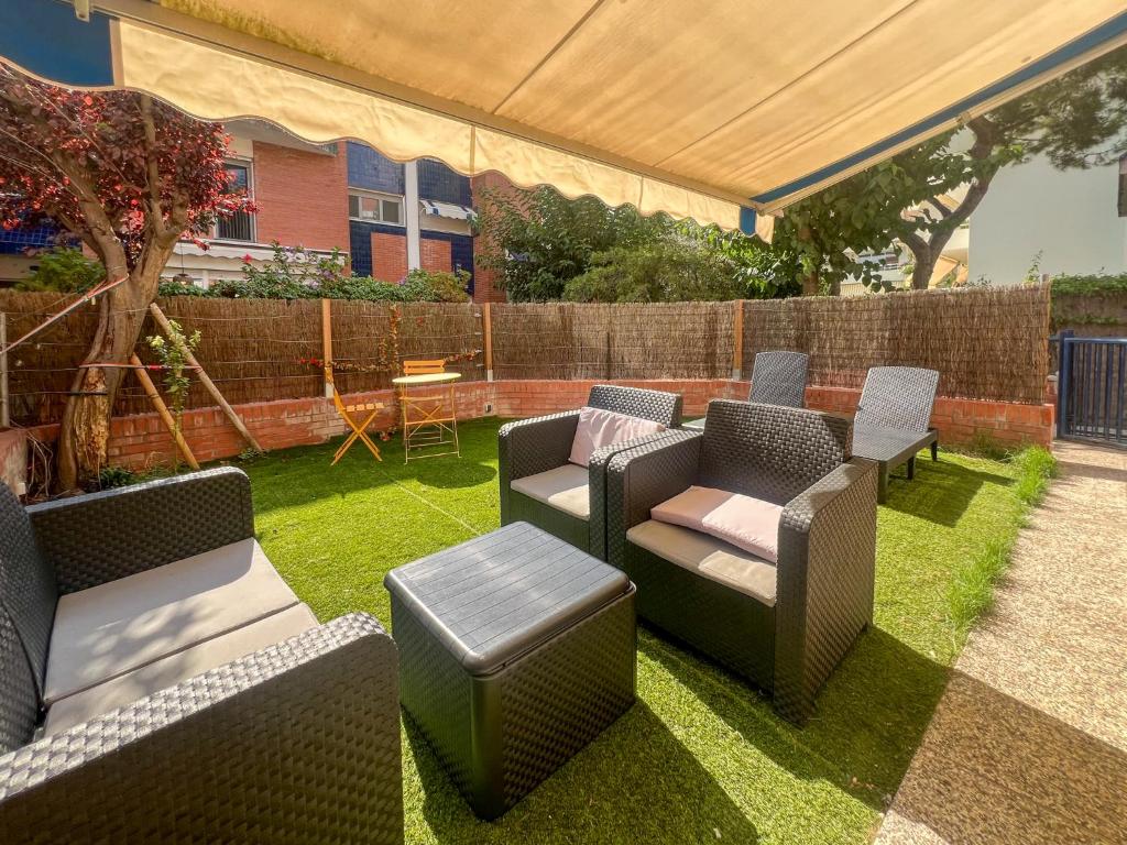 eine Terrasse mit Stühlen und Tischen auf dem Rasen in der Unterkunft Ocean Spirit House by Hello Homes Sitges in Sitges