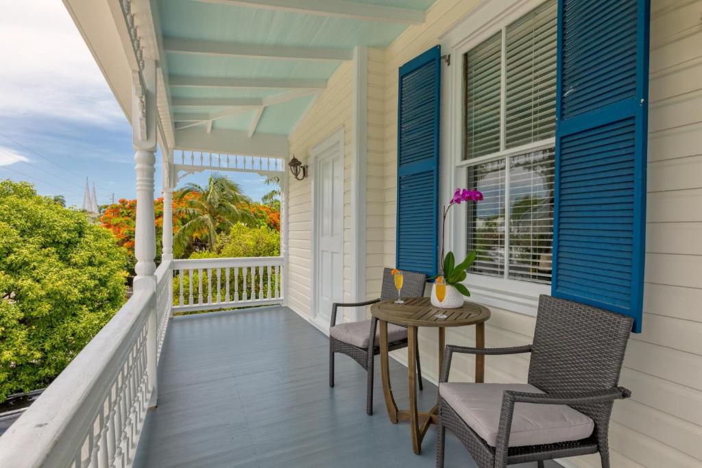 a porch with chairs and a table and a window at CAPTIVA at Azul Mansion Key West in Key West