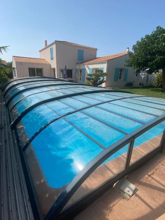 a blue swimming pool with a metal roof at Villa avec jardin et piscine 3 minutes de la Rochelle in Lagord