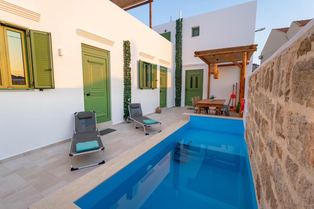 a house with a swimming pool and two chairs at Villa Emerald in Koskinou