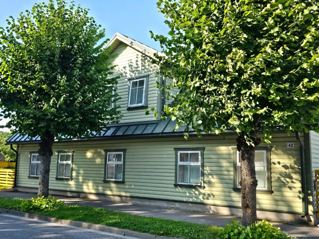 a green house with two trees in front of it at Rönne Majutus in Pärnu