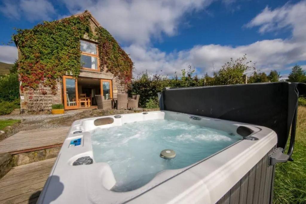 einen Whirlpool vor einem Haus in der Unterkunft The Barn on Loch Tay - Hot Tub in Lawers