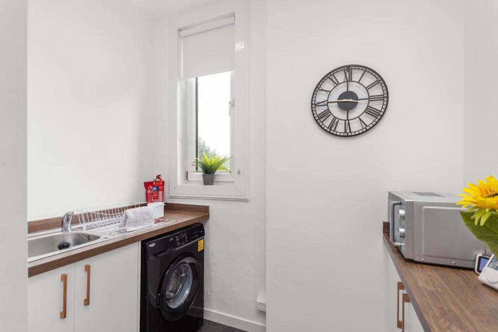 cocina con lavadora y reloj en la pared en Stylish Stay in Inverkeithing., en Fife