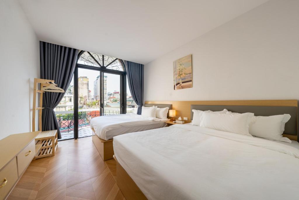 a hotel room with two beds and a window at Starlight Hotel Hanoi in Hanoi