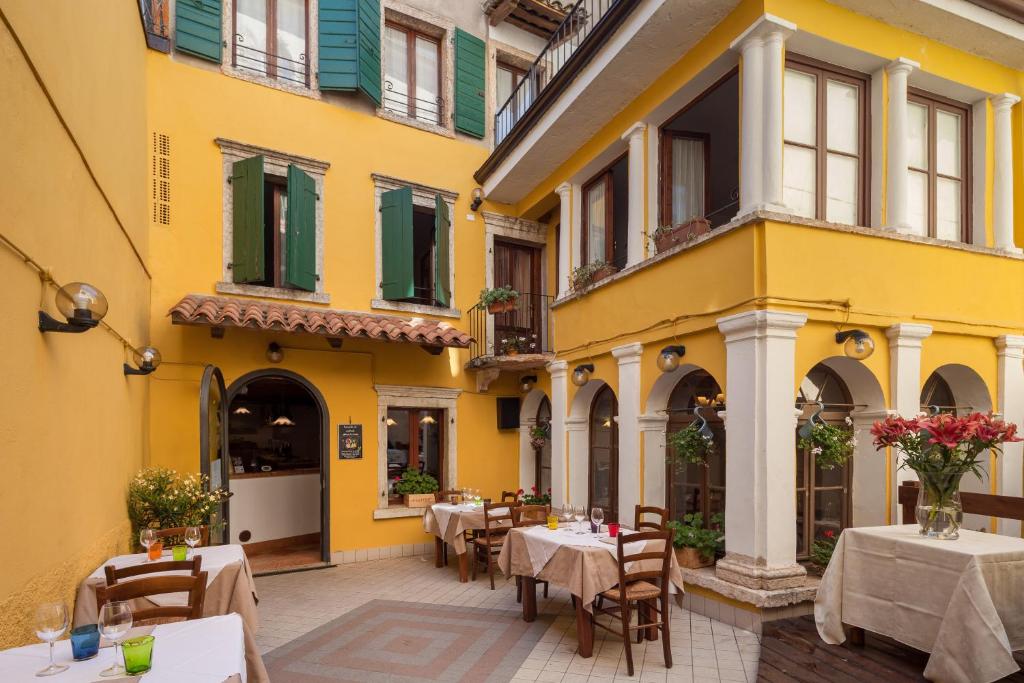 ein gelbes Gebäude mit Tischen und Stühlen im Innenhof in der Unterkunft Locanda Al Centrale in Caprino Veronese
