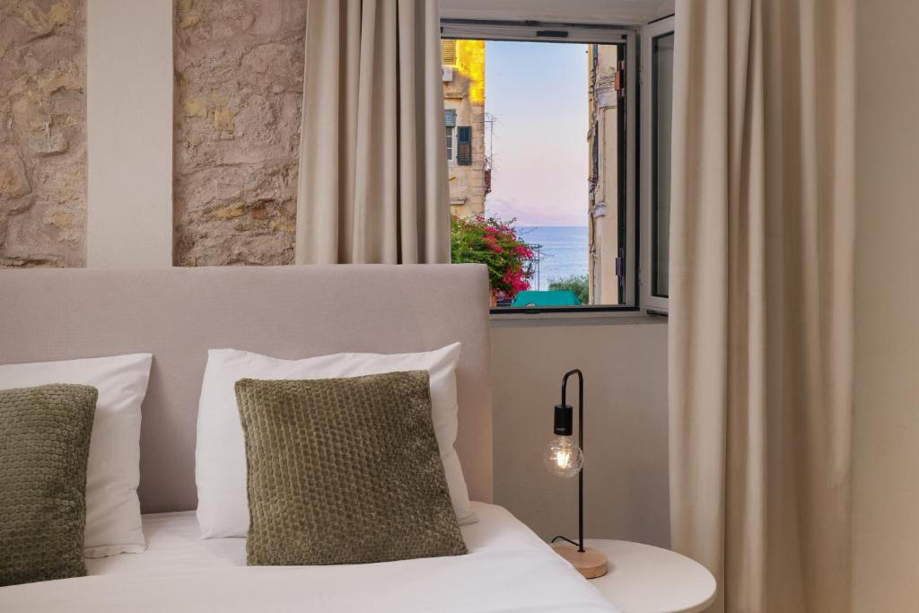 ein Schlafzimmer mit einem weißen Bett mit einem Fenster in der Unterkunft Dousmani Old Town Studio in Korfu-Stadt