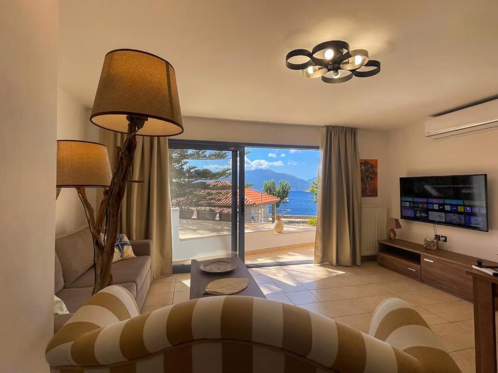 een woonkamer met een bank en een televisie met uitzicht op de oceaan bij GN apartment in Ayia Evfimia