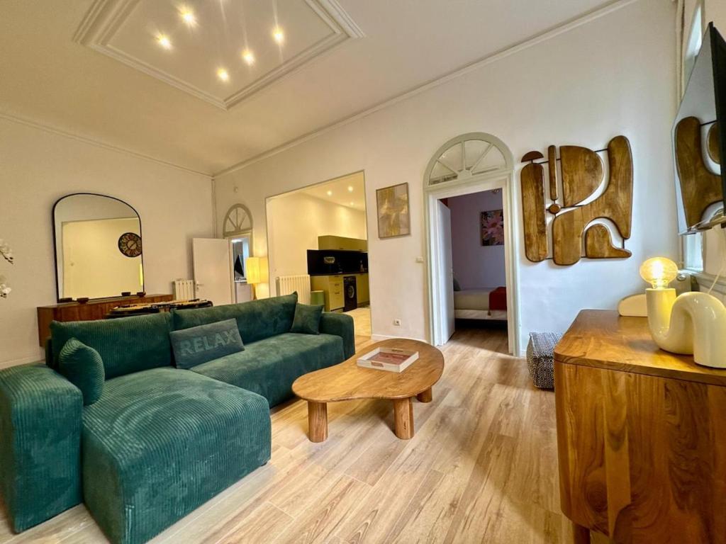 Una sala de estar con un sofá verde y una mesa. en Suite Madeleine - Cœur Historique, en Béziers