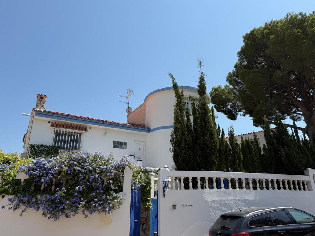 a white house with purple flowers on a fence at Villa El Faro in Peñíscola