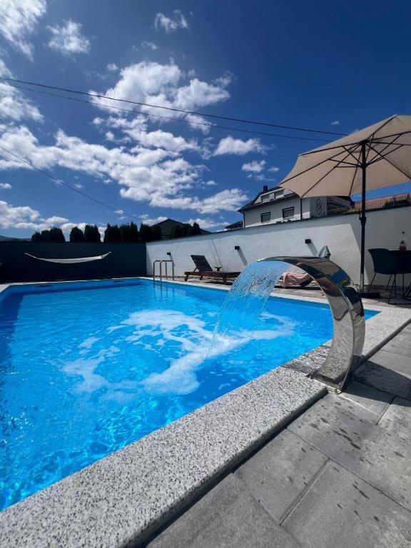 a swimming pool with a fountain in front of a house at Melissa luxury Apartment in Bijelo Brdo