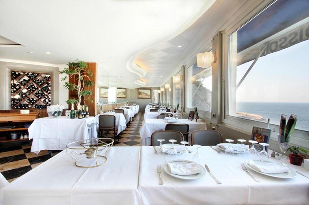 - un restaurant avec des tables blanches et une vue sur l'océan dans l'établissement Le Rhul, à Marseille