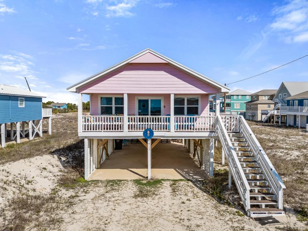 een roze huis op het strand naast enkele huizen bij Bikini Bottom in Gulf Shores