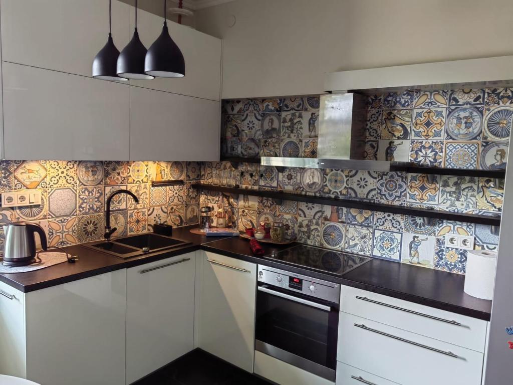 een keuken met witte kasten en blauwe en witte tegels bij Blakus bērnu pilsētiņai un pludmalei in Ventspils