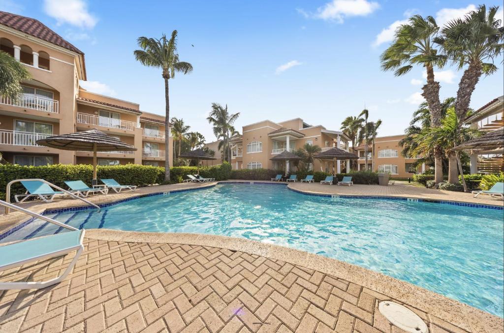 a swimming pool with palm trees and buildings at Divi Village Condo 31 in Palm-Eagle Beach